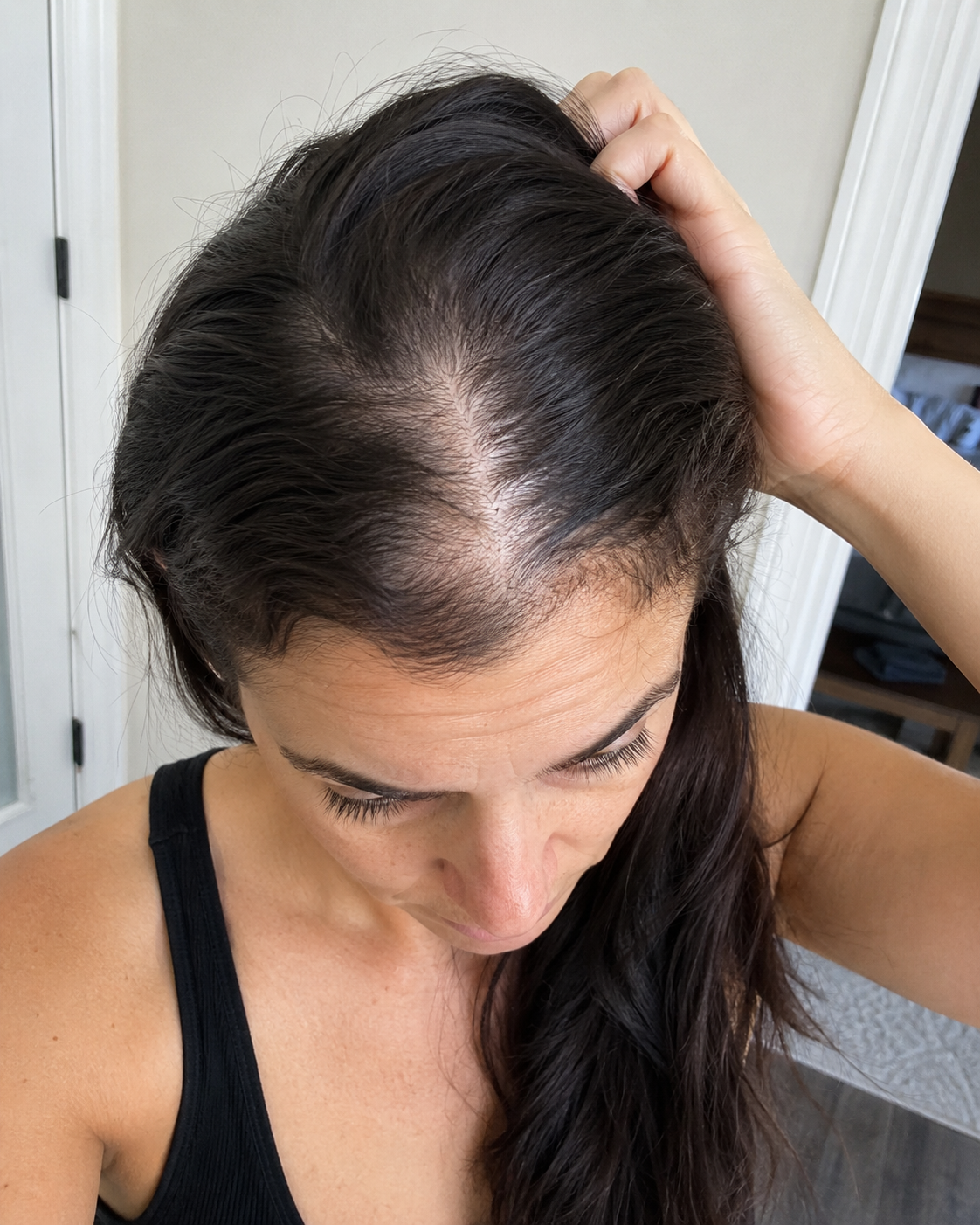 Close-up of a woman's parting showing visible scalp through her hair